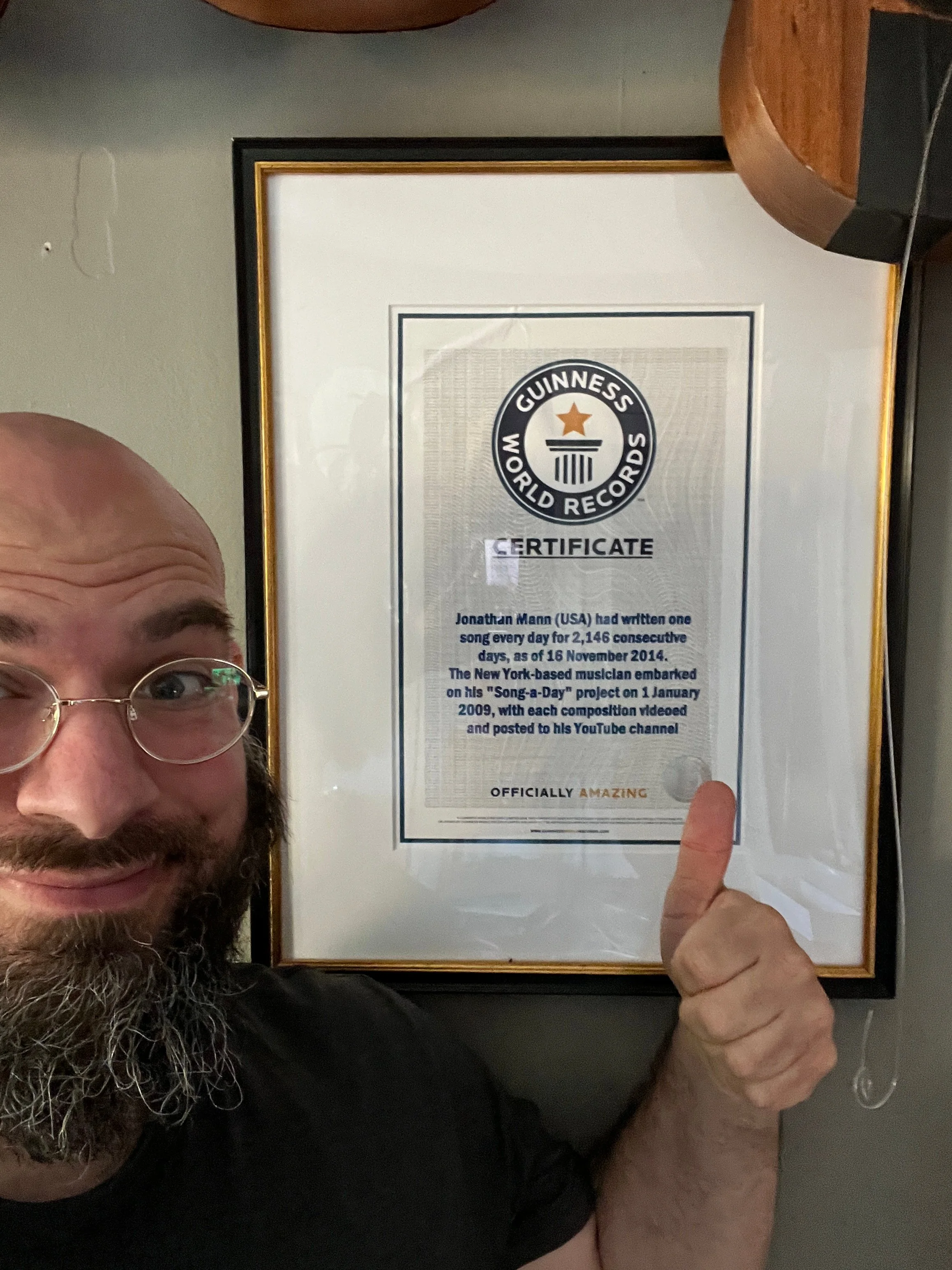 Jonathan Mann holding up his Guinness World Records certificate